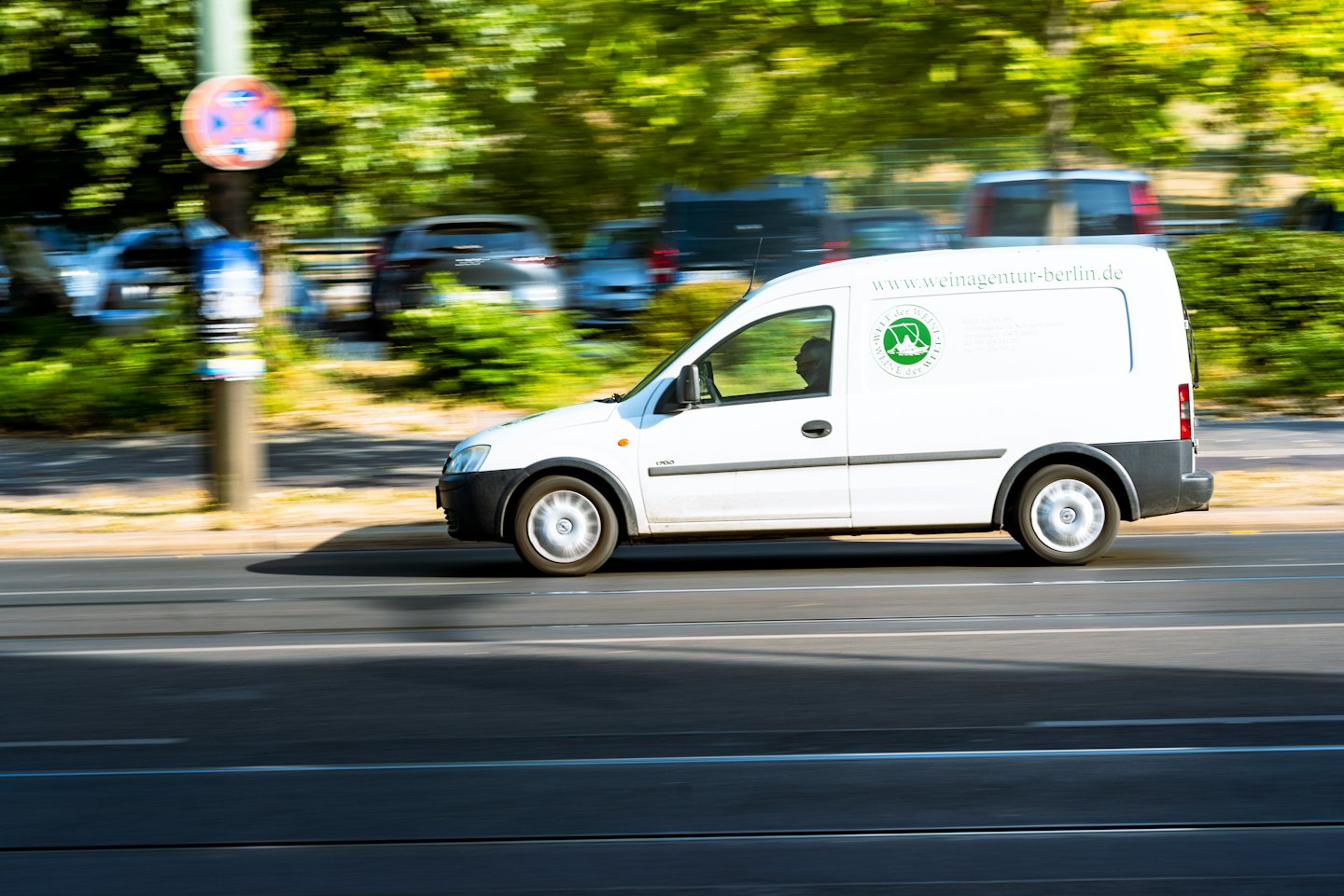 Delivery van with a green logo driving on city street.
