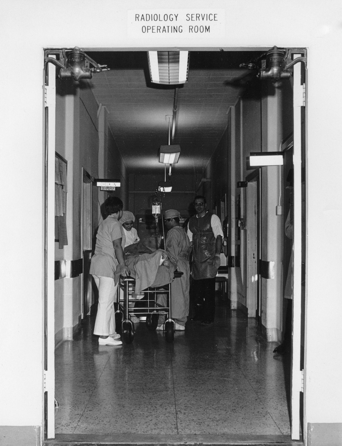 Medical staff transport a patient on a gurney through a hospital hallway.