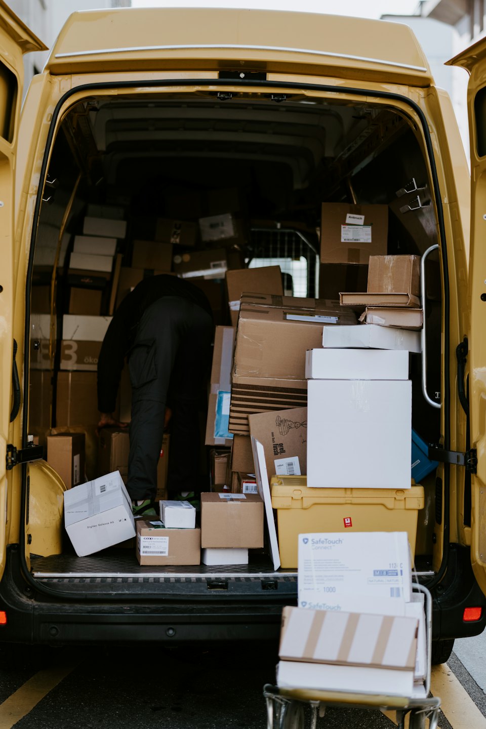 Delivery person organizing boxes in a yellow van.